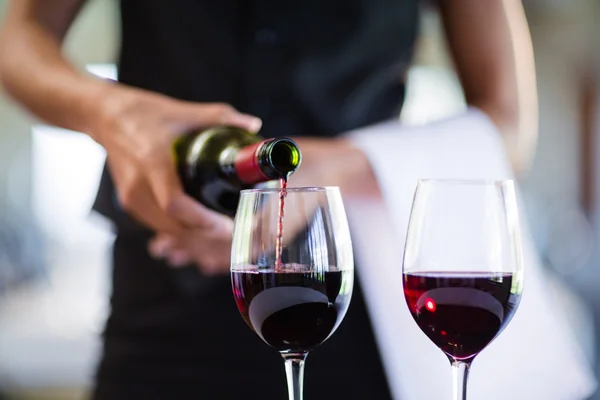 waitress pouring red wine in glass