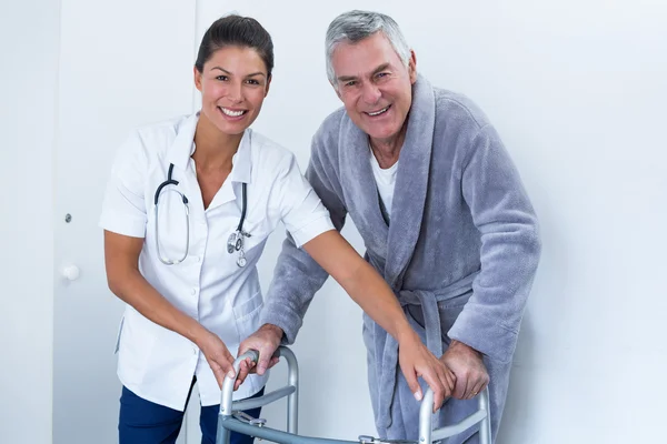 Kvinnliga läkare att hjälpa äldre mannen att gå med rullator — Stockfoto