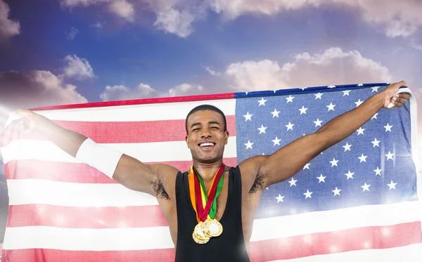 Imagen compuesta de atleta sosteniendo medallas de oro y bandera americana — Foto de Stock