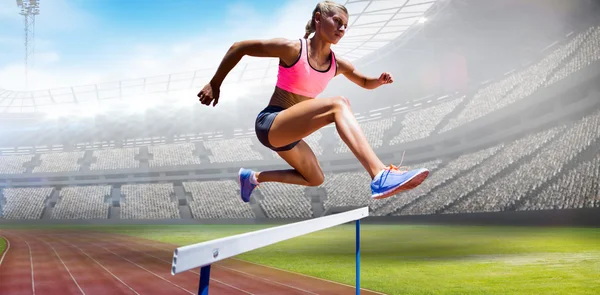 Sporty woman jumping hurdle — Stock Photo, Image