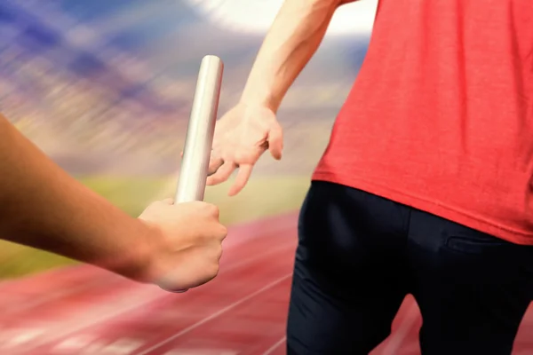 Athlete passing baton to partner — Stock Photo, Image