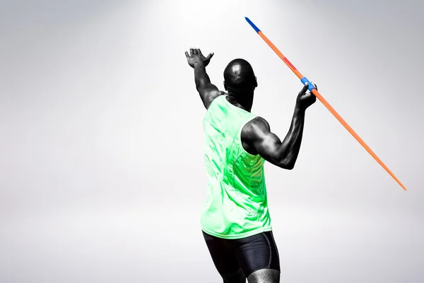 Man throwing javeline against grey — Stock Photo, Image