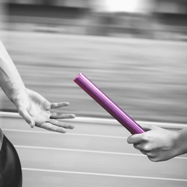 Athlete passing baton to partner — Stock Photo, Image