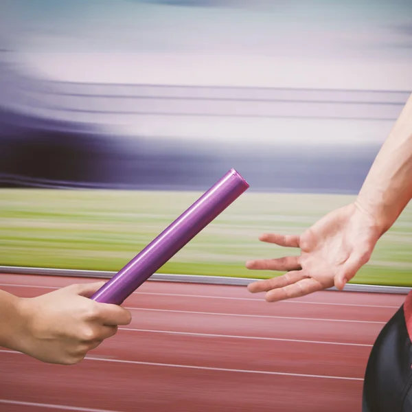 Atleta passando bastão para parceiro — Fotografia de Stock