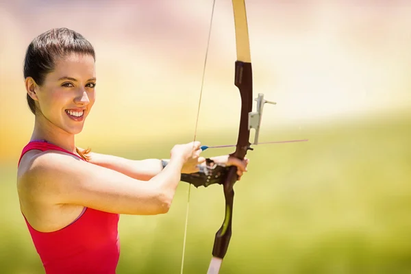 Sportlerin lächelt und praktiziert Bogenschießen — Stockfoto