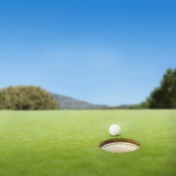 구멍의 가장자리에 골프 공 — 스톡 사진