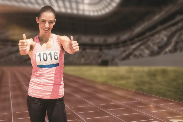 Atletisk kvinde smilende med tommelfingre op - Stock-foto