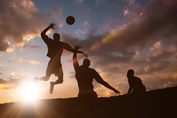 Sportsmen playing volleyball against clouds — Stock Photo, Image