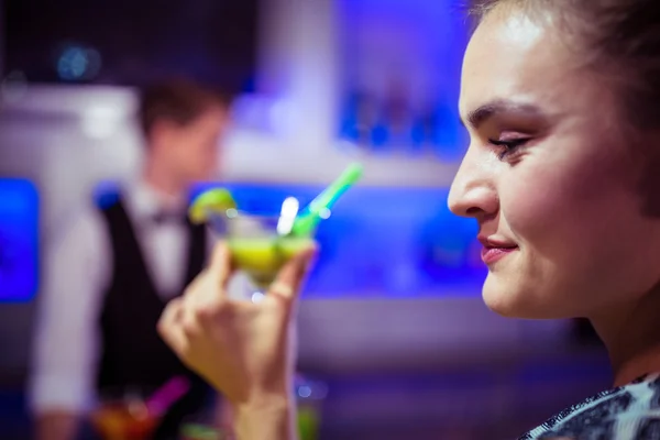 Woman holding cocktail glass against bartender — Stock Photo, Image