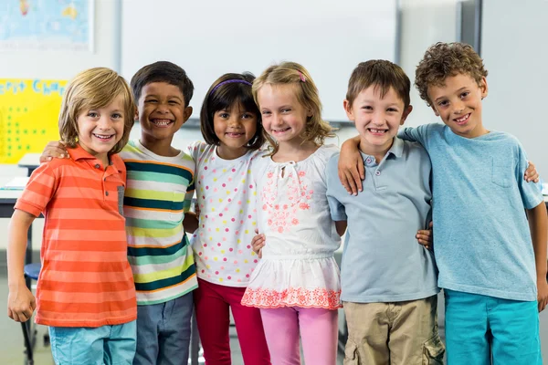 Happy schoolchildren standing in classroom — Stock Photo, Image