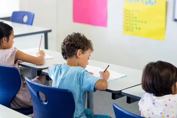 Los escolares que escriben en el libro en el aula — Foto de Stock