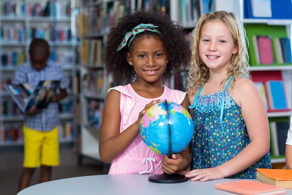 Ragazze sorridenti con globo sul tavolo — Foto Stock