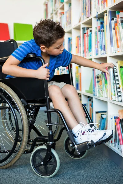 Gehandicapte jongen boeken in bibliotheek zoeken — Stockfoto