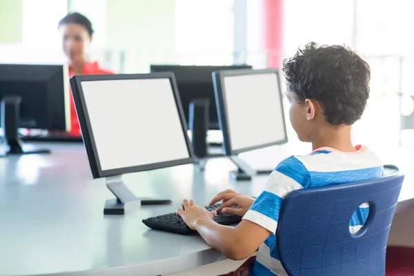 Jongen met behulp van de computer tegen vrouwelijke leraar — Stockfoto