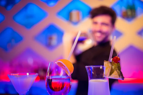 Напитки на стойке во время бармена на заднем плане — стоковое фото