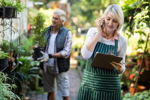 Jardinero hablando por teléfono móvil mientras el hombre —  Fotos de Stock