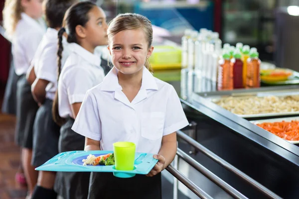 Schoolgirl with classmate standing near canteen counter — Stock Photo, Image