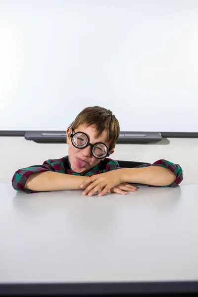 Rapaz brincalhão fazendo um rosto na sala de aula — Fotografia de Stock
