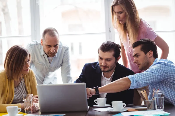 Empresario explicando a los compañeros de trabajo utilizando el ordenador portátil — Foto de Stock