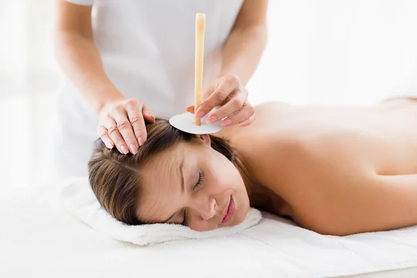 Masseur giving ear candle treatmet to woman — Stock Photo, Image