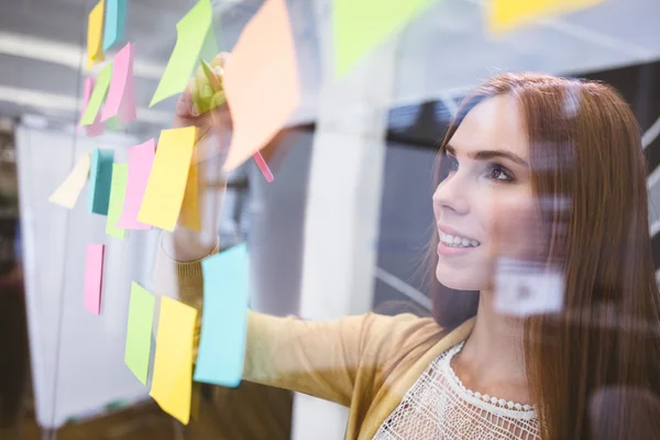 Business woman writing on sticky notes — стоковое фото