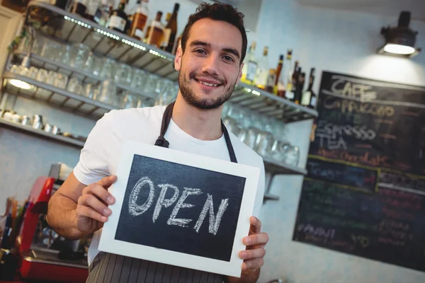 Barista segurando quadro negro na cafetaria — Fotografia de Stock