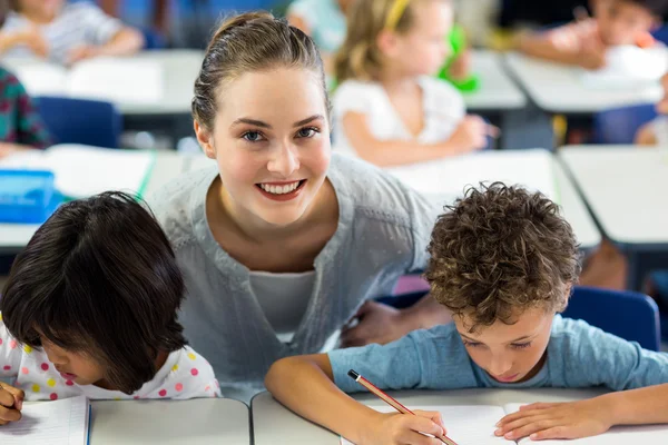 Vrouwelijke leraar helpt schoolkinderen — Stockfoto