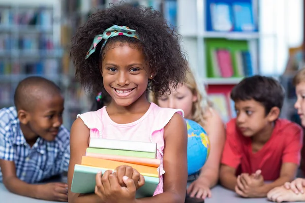 Menina segurando livros contra colegas de classe — Fotografia de Stock