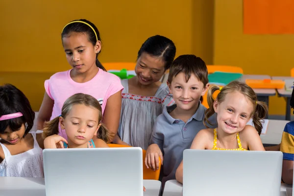 Niños sonrientes usando computadoras portátiles —  Fotos de Stock