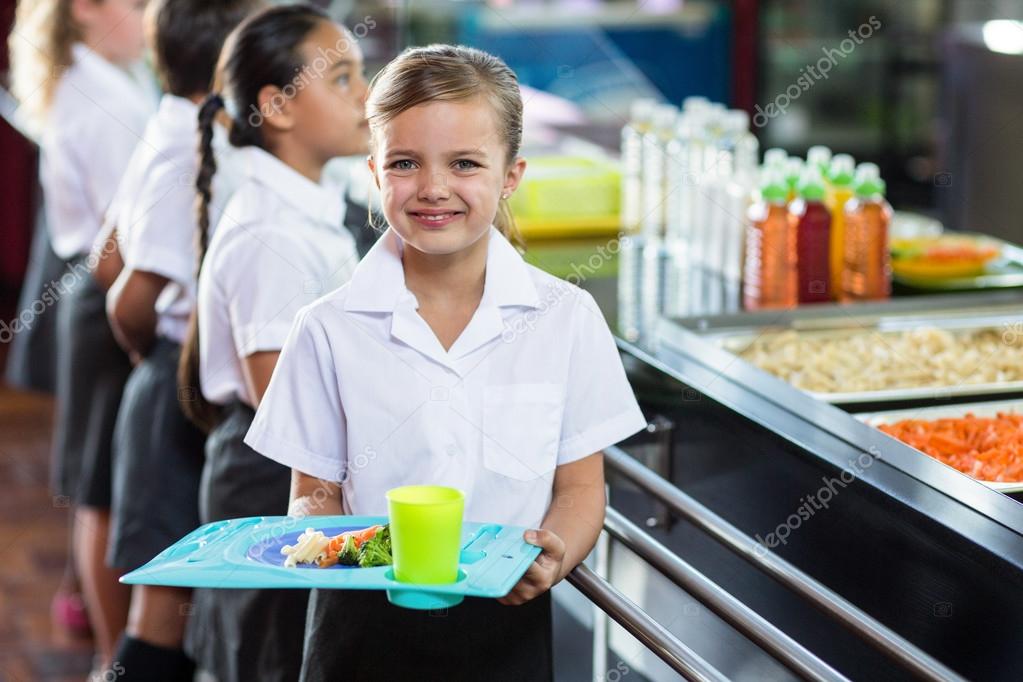 Schoolgirl with classmate standing near canteen counter Stock Photo by