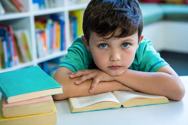 Elementarne chłopiec z książki w szkolnej bibliotece — Zdjęcie stockowe