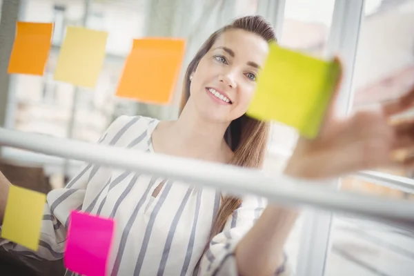 Femme d'affaires regardant des notes adhésives — Photo