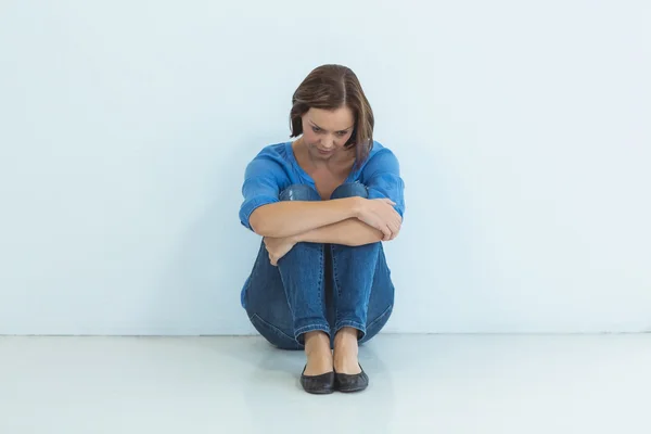 Treurige vrouw zitten tegen muur — Stockfoto