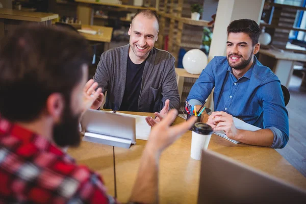 Empresários sorrindo discutindo na mesa — Fotografia de Stock