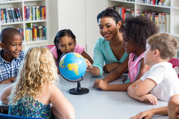 Female teacher teaching children using globe — Stock Photo, Image