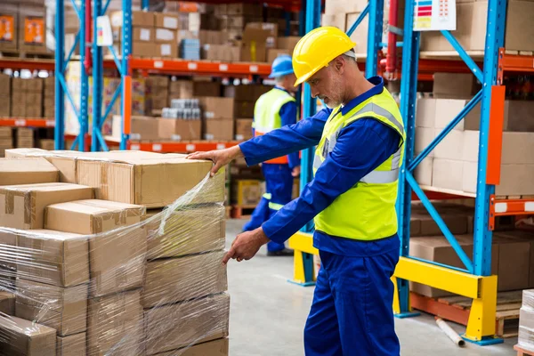 Trabajador abriendo un plástico para las cajas — Foto de Stock