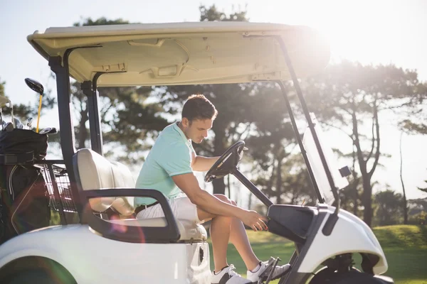 Golfista człowiek siedzi w golf buggy — Zdjęcie stockowe