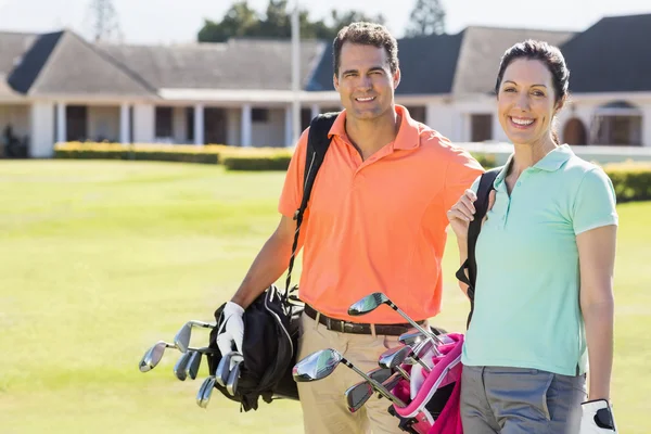 Pareja llevando bolsas de golf — Foto de Stock