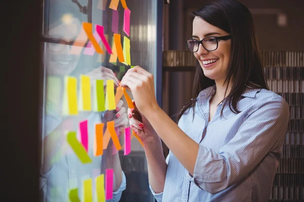 Businesswoman sticking adhesive notes — Stock Photo, Image