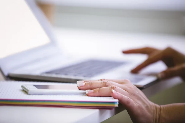 Zakenvrouw met cellphone terwijl het gebruiken van laptop — Stockfoto