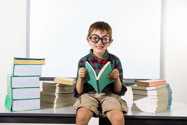 Boy holding book while sitting in classroom — Stock Photo, Image