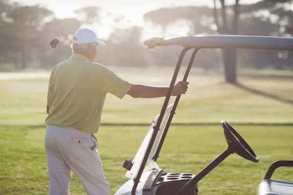 Зрелый мужчина, стоящий на багги для гольфа — стоковое фото