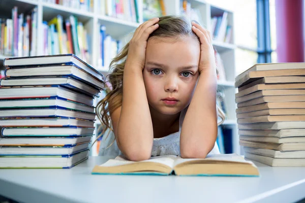 Стрессовая девушка с книгами за столом — стоковое фото