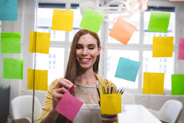 Business woman writing on sticky notes — стоковое фото