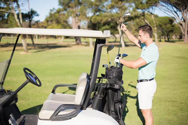 Homem colocando clube de golfe no saco — Fotografia de Stock