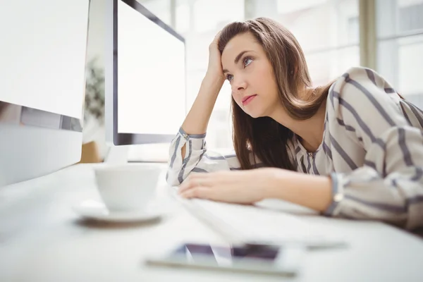 Businesswoman looking at computer in creative office — Stock Photo, Image