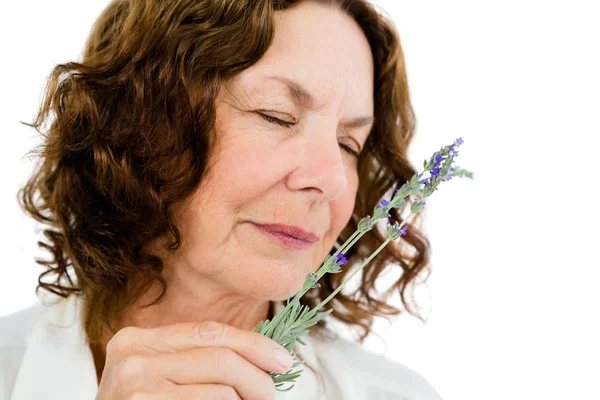 Mulher madura cheirando flores — Fotografia de Stock