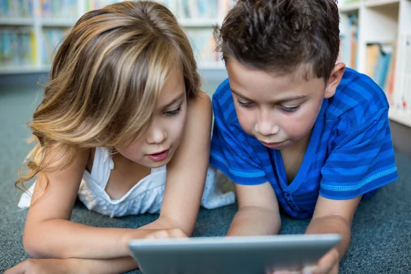 Niña y niño usando tableta en la biblioteca — Foto de Stock