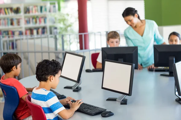 Niños usando computadoras como maestro enseñándoles —  Fotos de Stock