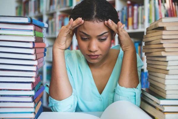 Stressed woman sitting amidst books — Stock Photo, Image